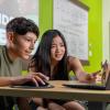 A teenage boy and girl coding on a laptop