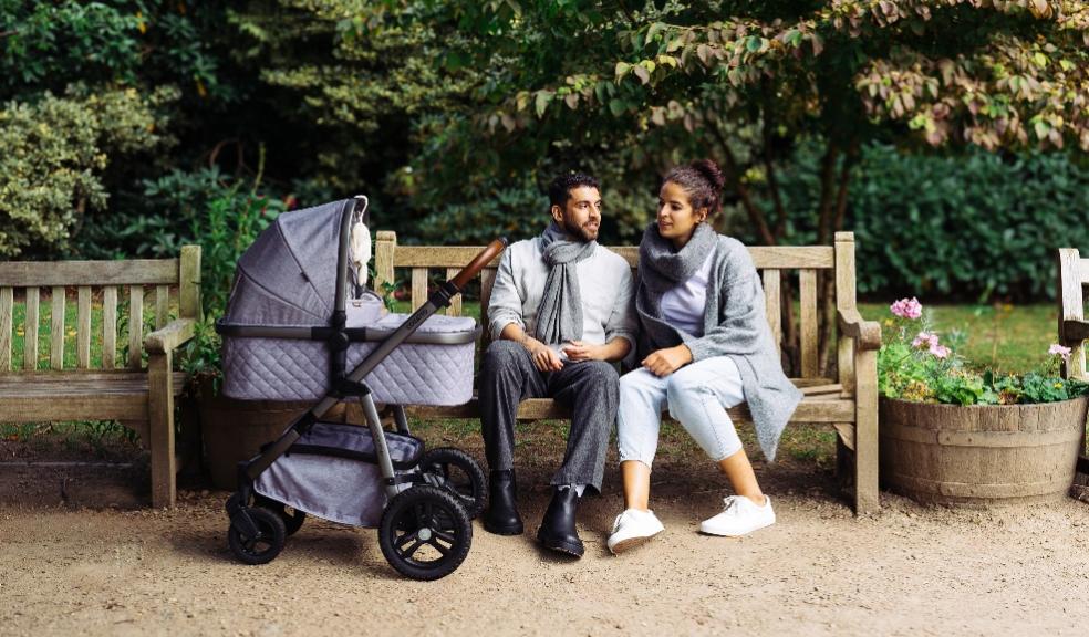 picture of a a couple sat on a beautiful bench outside with their baby in a Cosatto Wow 3 pram