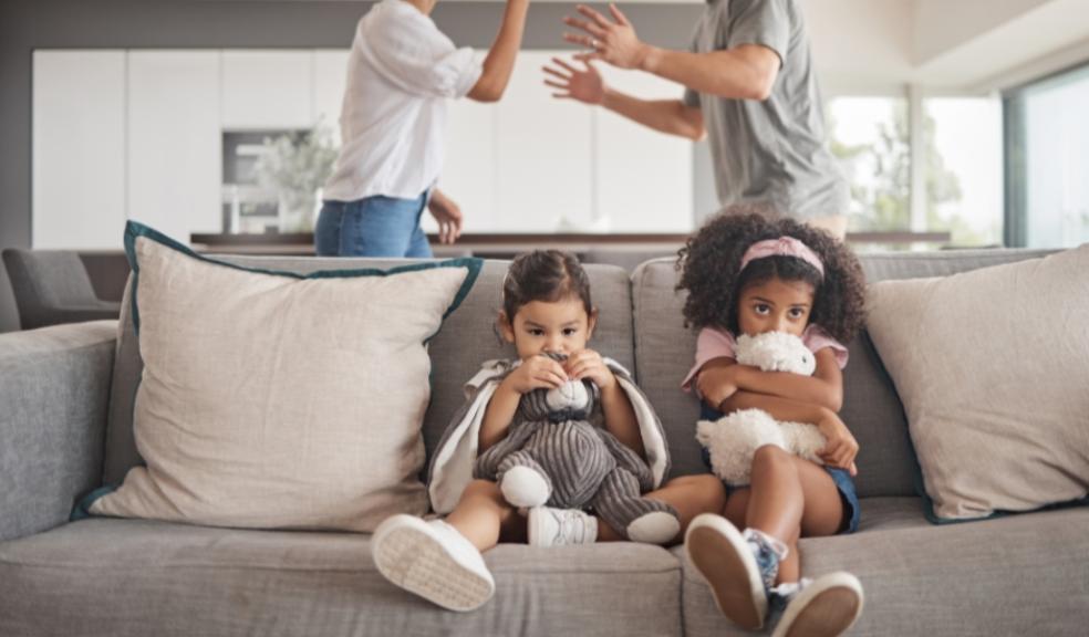 picture of children on the sofa with parents arguing behind them