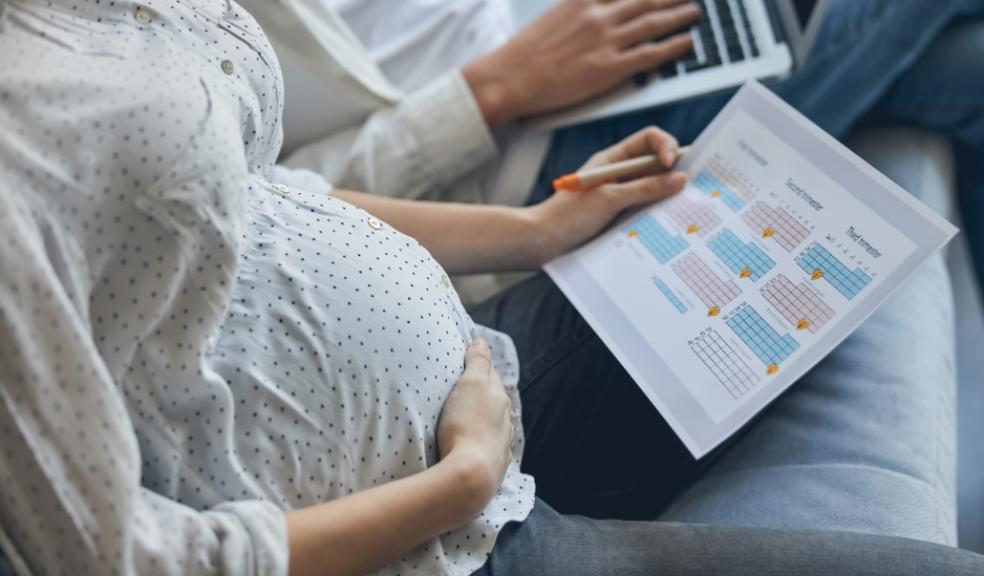 picture of a couple planning for maternity leave with a calendar and laptop