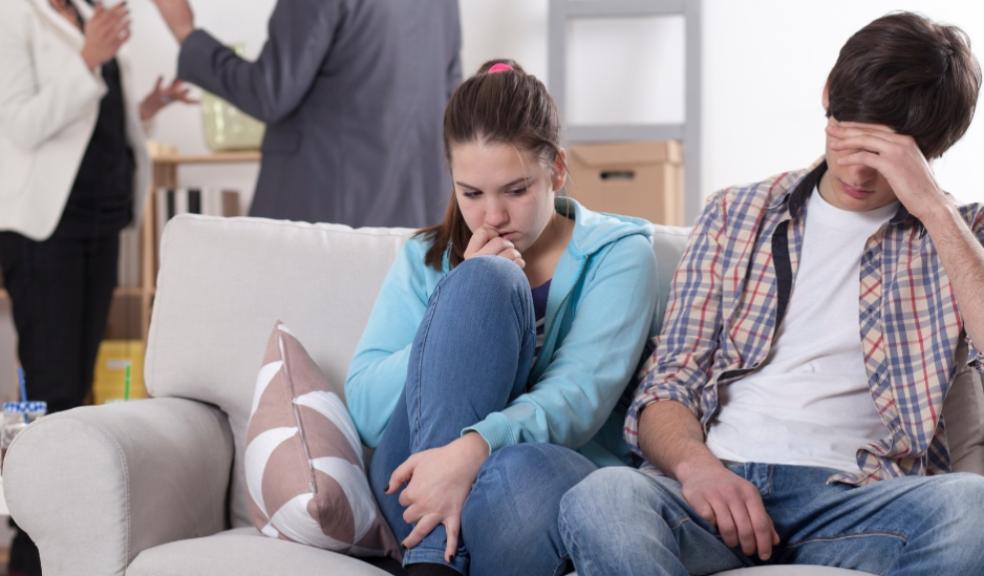 picture of teens on a sofa with parents arguing behind them