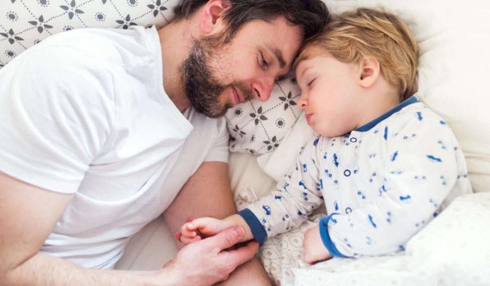 picture of dad laying in bed getting child to sleep