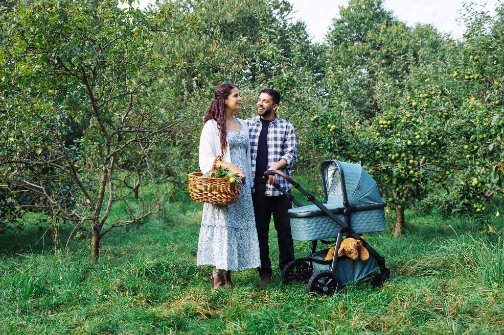 picture of a happy couple in an orchard with their baby in a Cosatto wow 3 pram