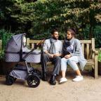 picture of a a couple sat on a beautiful bench outside with their baby in a Cosatto Wow 3 pram