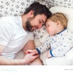 picture of dad laying in bed getting child to sleep