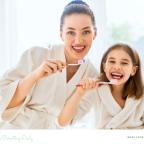 picture of a happy mum and daughter brushing their teeth together