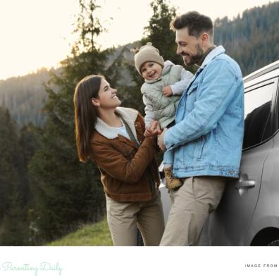 picture of a happy couple and a baby in front of their family car