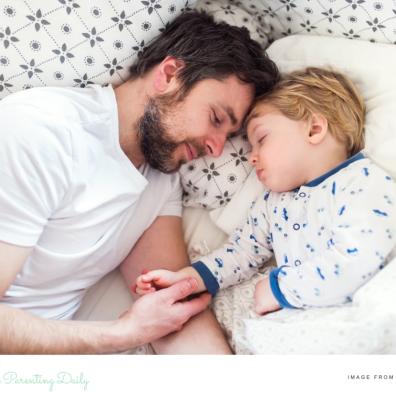 picture of dad laying in bed getting child to sleep