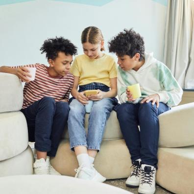 picture of three children sat together looking at a smartphone