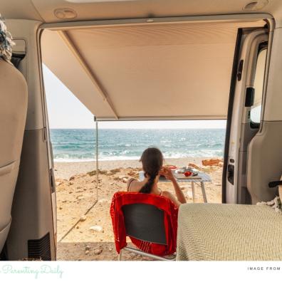 picture of a woman sat outside a caravan with a sunny beach scene